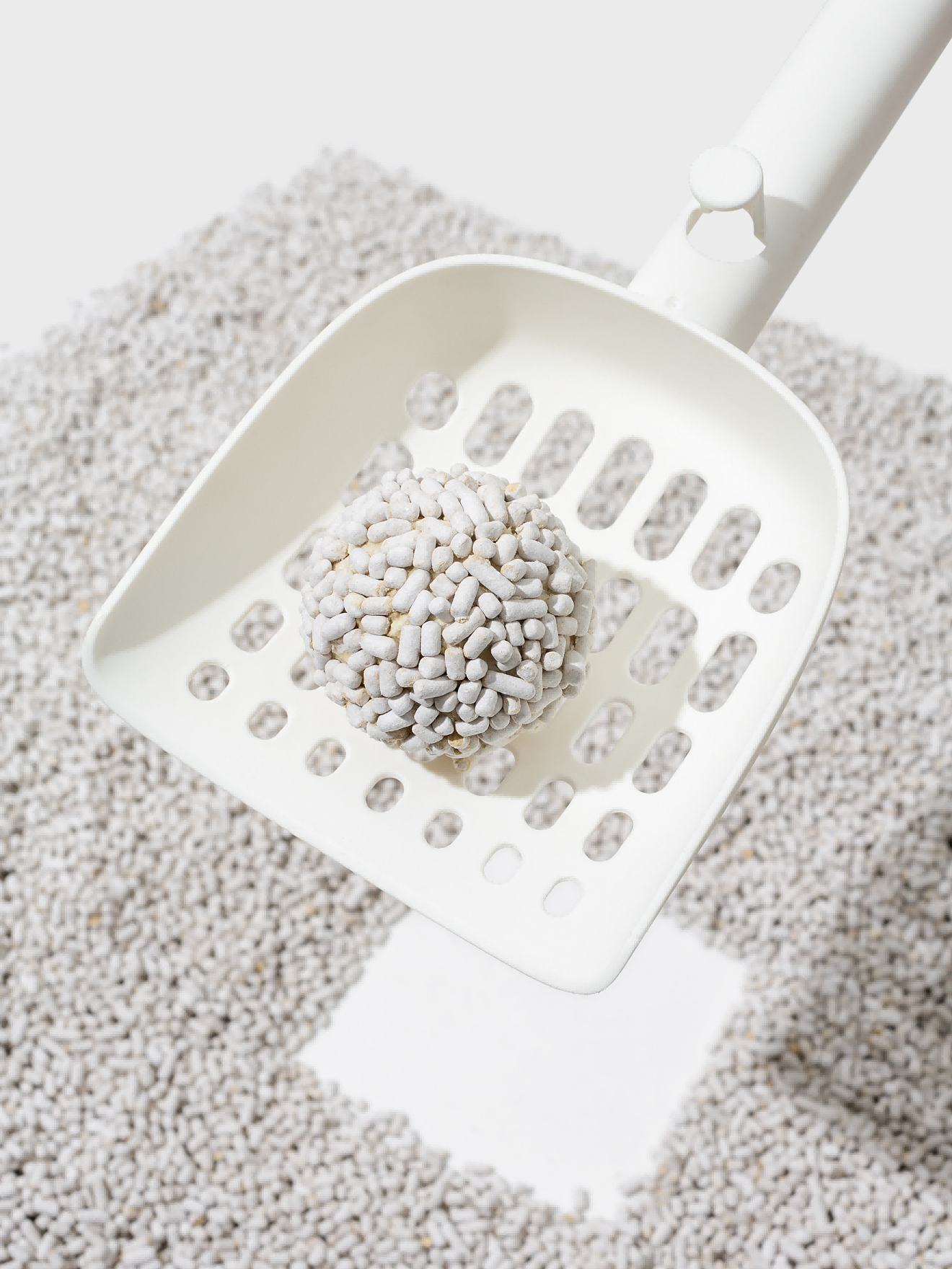 Scooping clumped cat litter with a litter scoop.